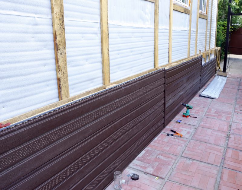 Installation of brown plastic siding on the facade